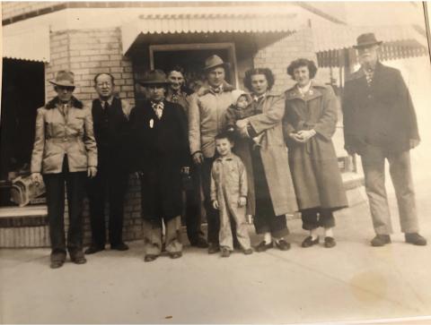 an old sepia picture of a group of people standing in front of a brick building