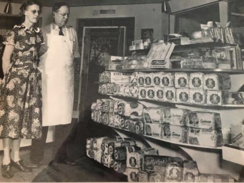 an old sepia picture of two people in a grocery store