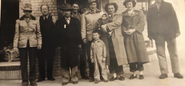 an old sepia picture of a group of people standing in front of a brick building